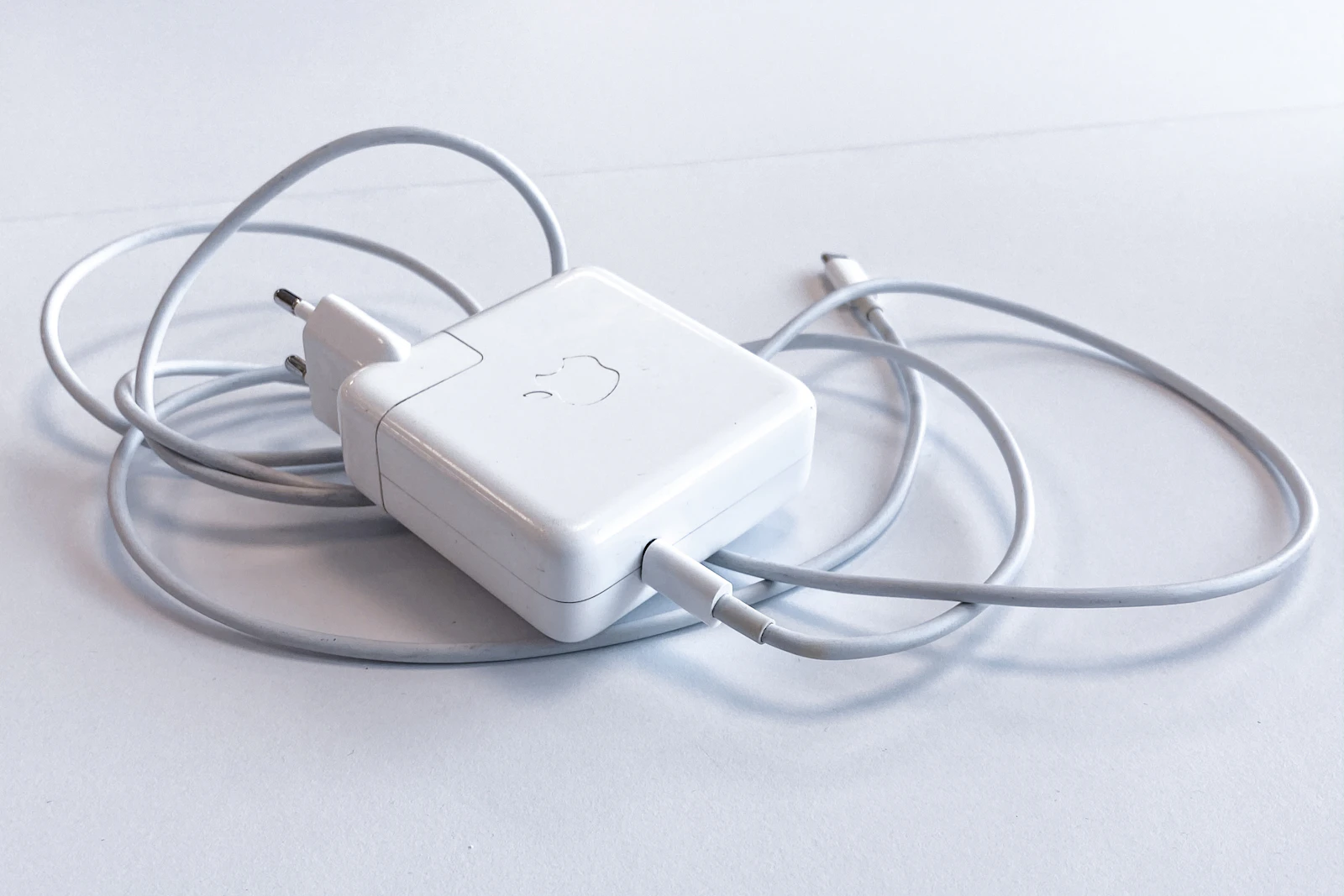 Kabel pengisi daya putih dan adaptor daya di atas permukaan terang