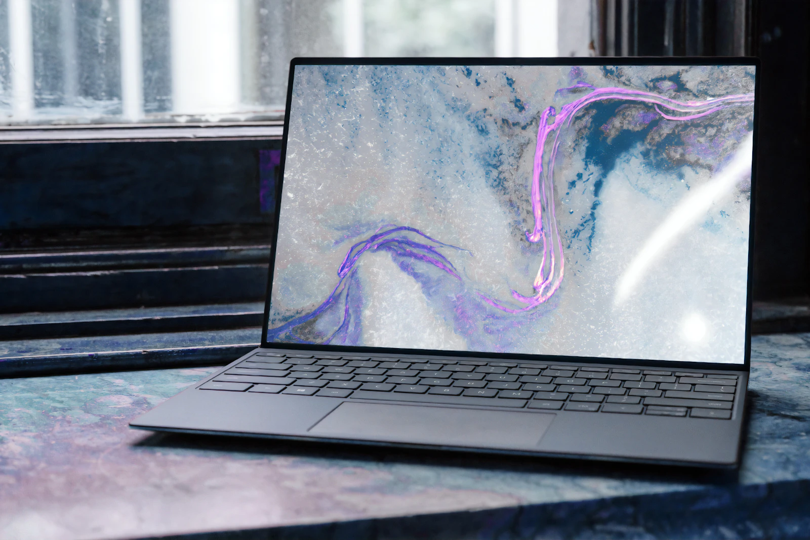 Meja minimalis dengan monitor, keyboard, dan tanaman di samping jendela